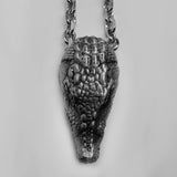 A small silver alligator head in the perspective of looking down. Bumpy, 3 dimensional scales give it a realistic feel.